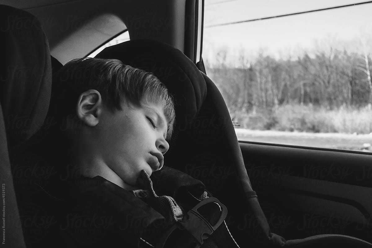 Boy sleeping in car.