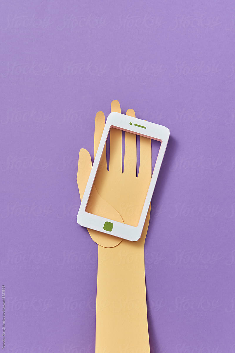 Cut paper hand holds white handcraft smartphone.