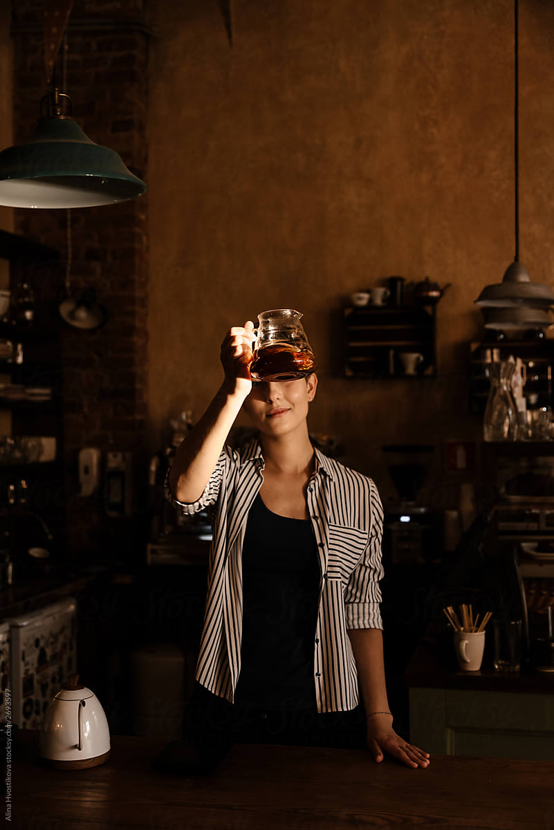Pretty female holding glasses kettle with coffee.
