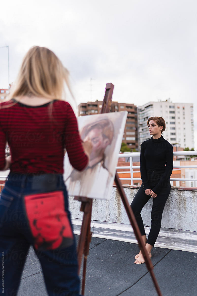 An artist painting a model on rooftop