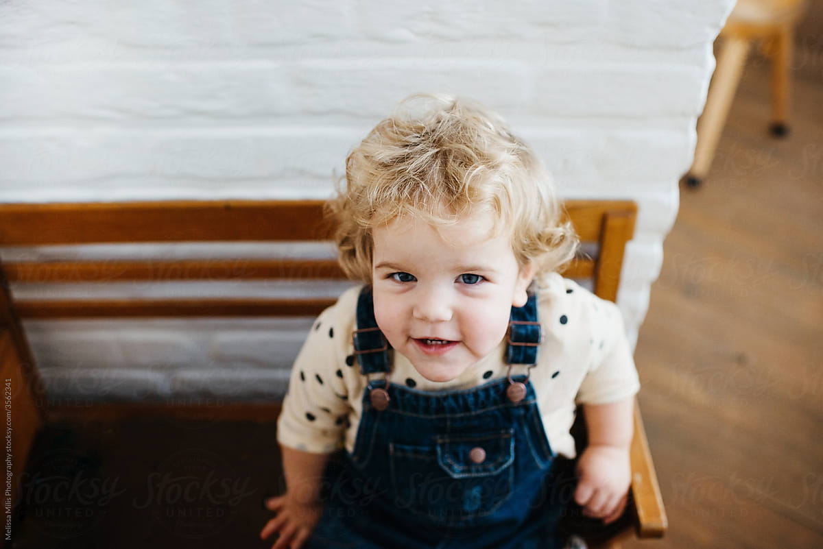 sweet little girl with curls on a vintage wooden bench