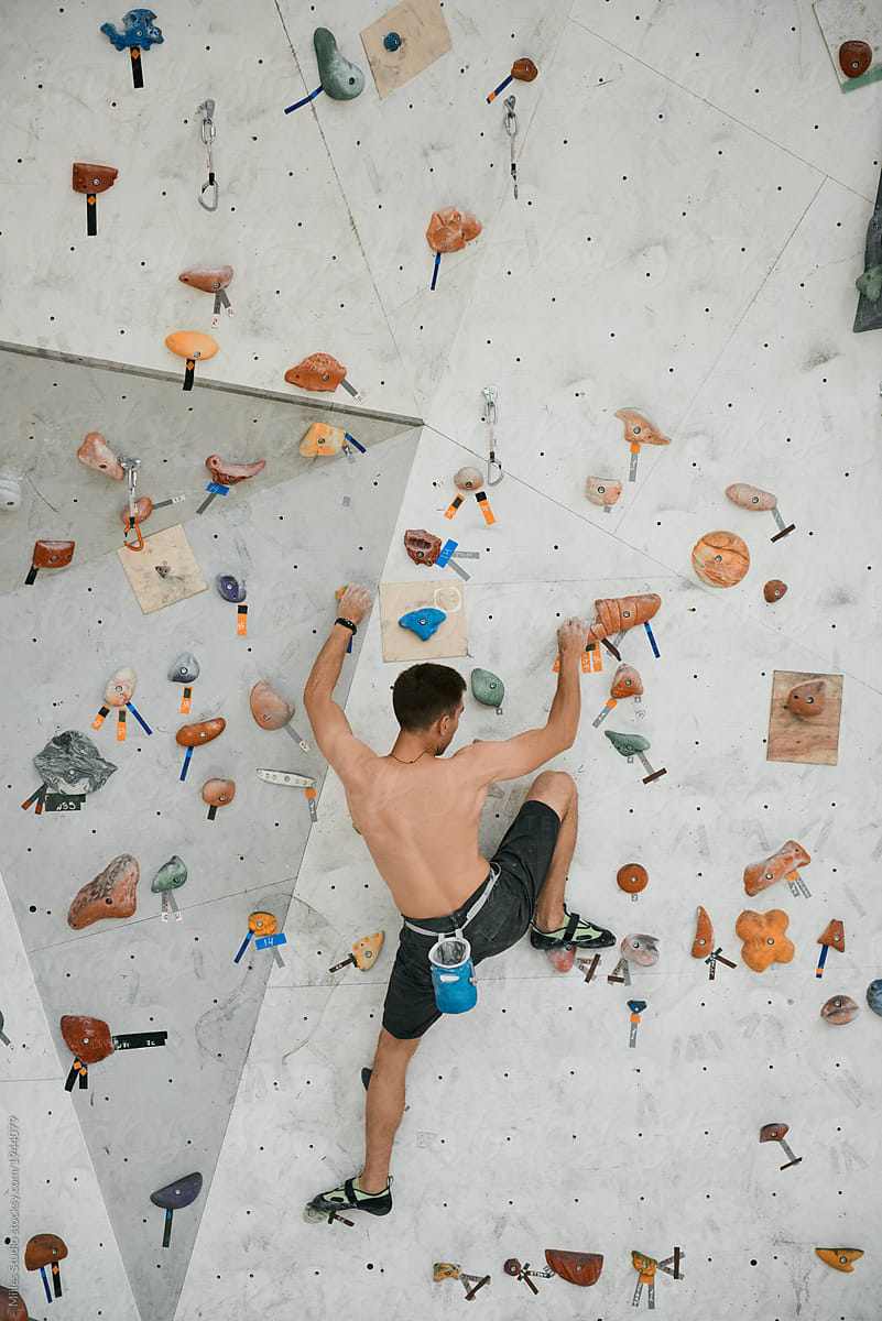 Shirtless athlete climbing on wall