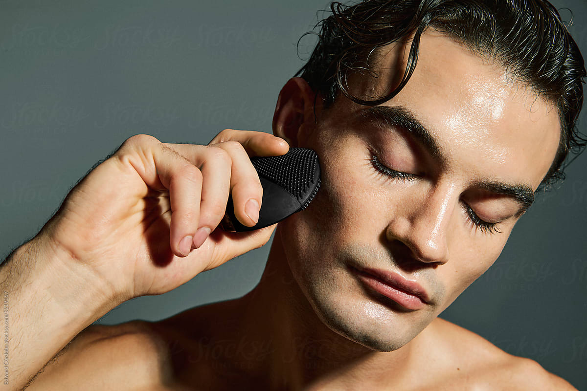 Man using face cleansing brush. Male Skincare