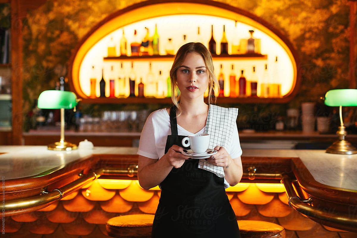 Portrait of a blonde waitress standing in a restaurant.