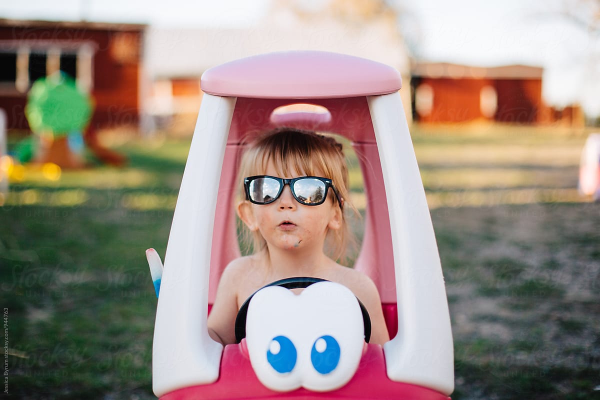 Little girl making a funny face in pink toy car