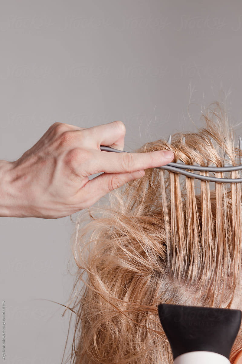 Unrecognizable man dries and styles a woman's hair