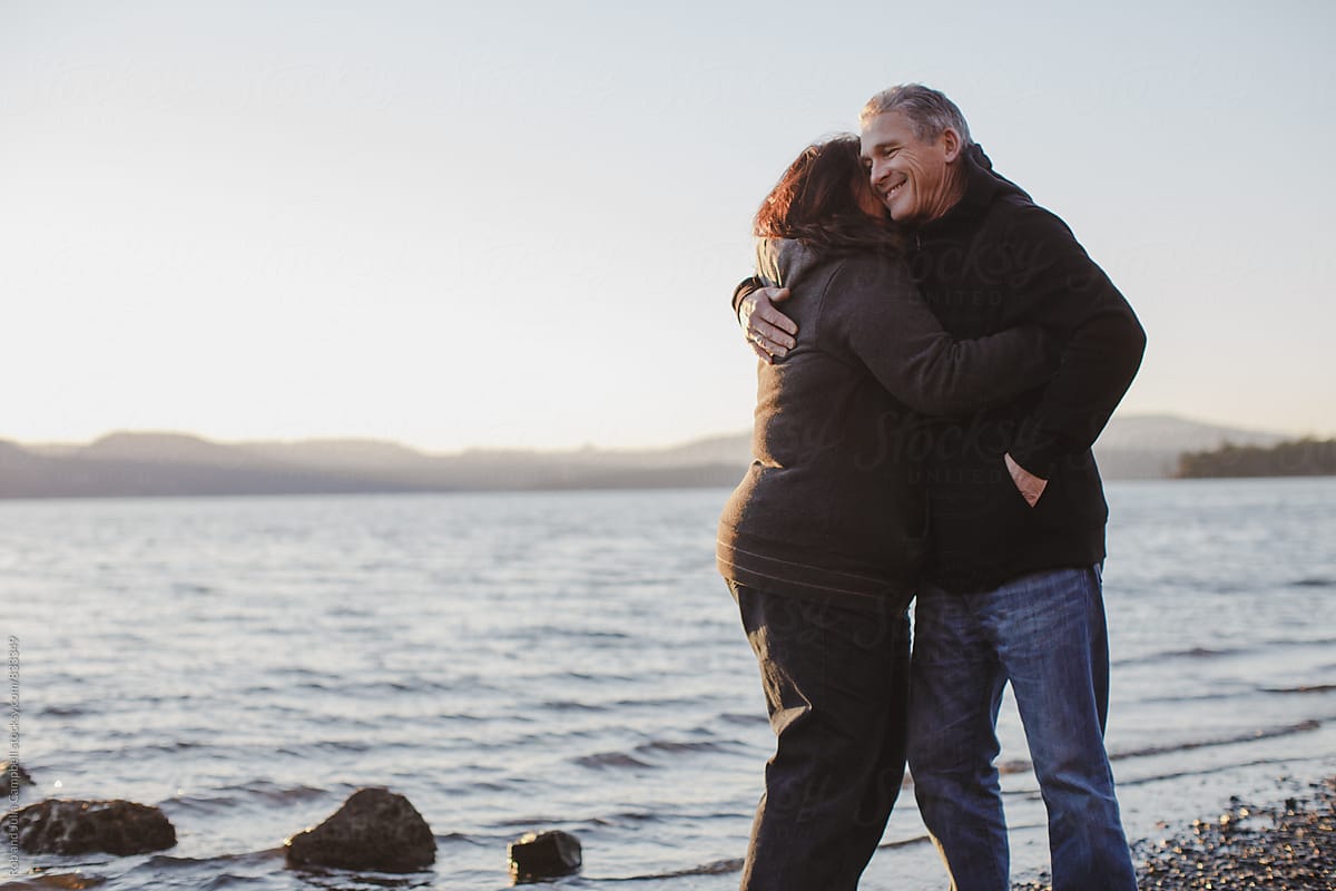 Happy Mature Couple Enjoying Hugging Each Other At The Beach At Sunset By Stocksy Contributor