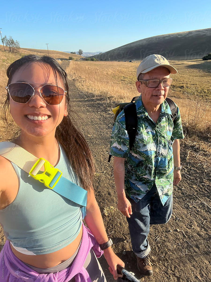 Selfie of dad and adult daughter on a sunny hike with dog