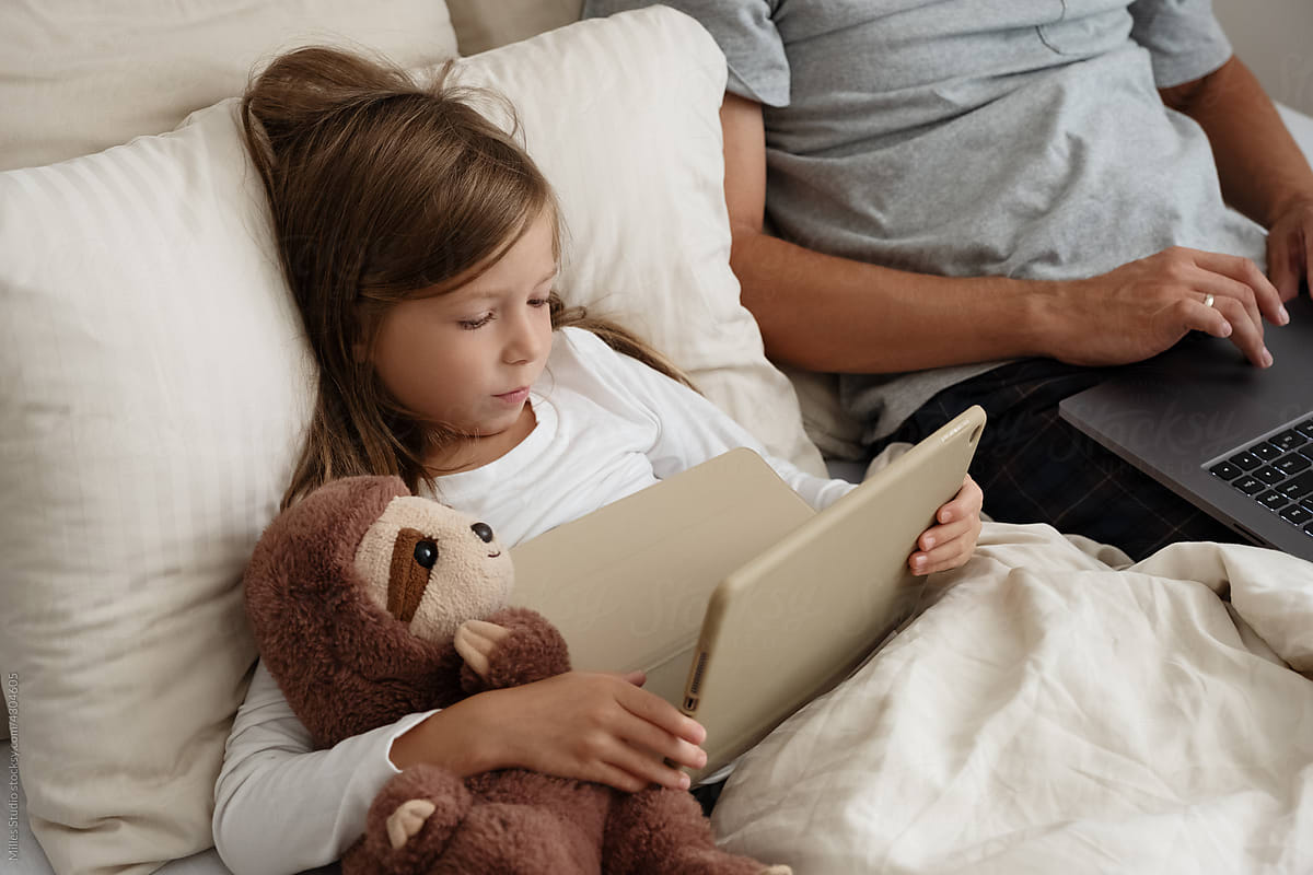 Daughter with toy using tablet near working dad