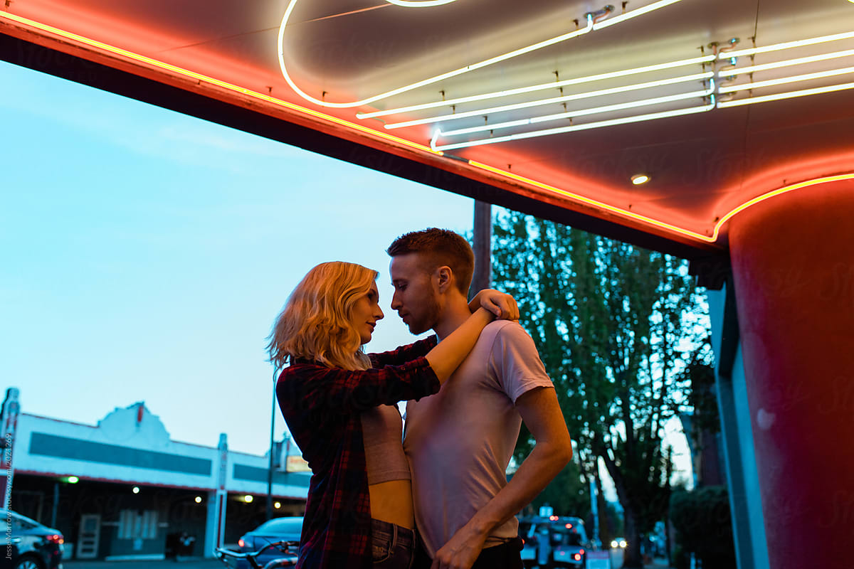 young couple hugs under neon light