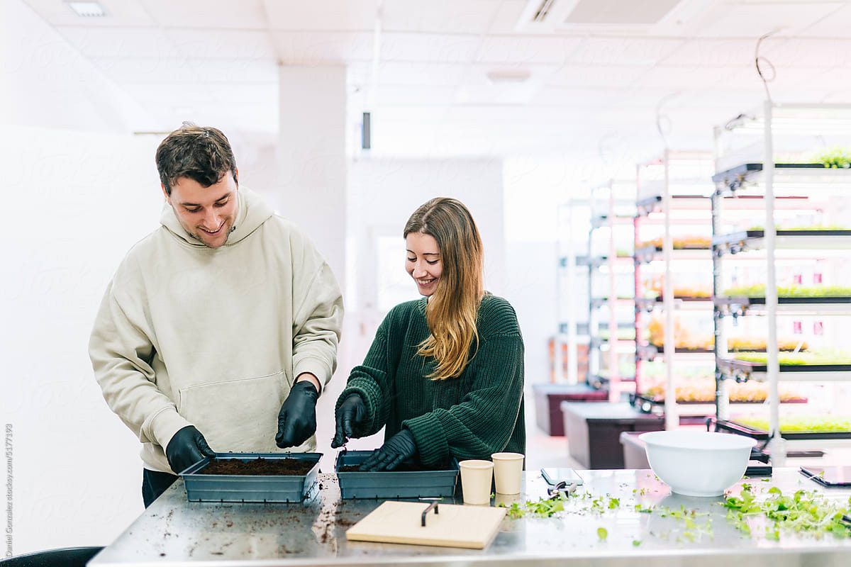 Smiling couple preparing soil for planting in lab