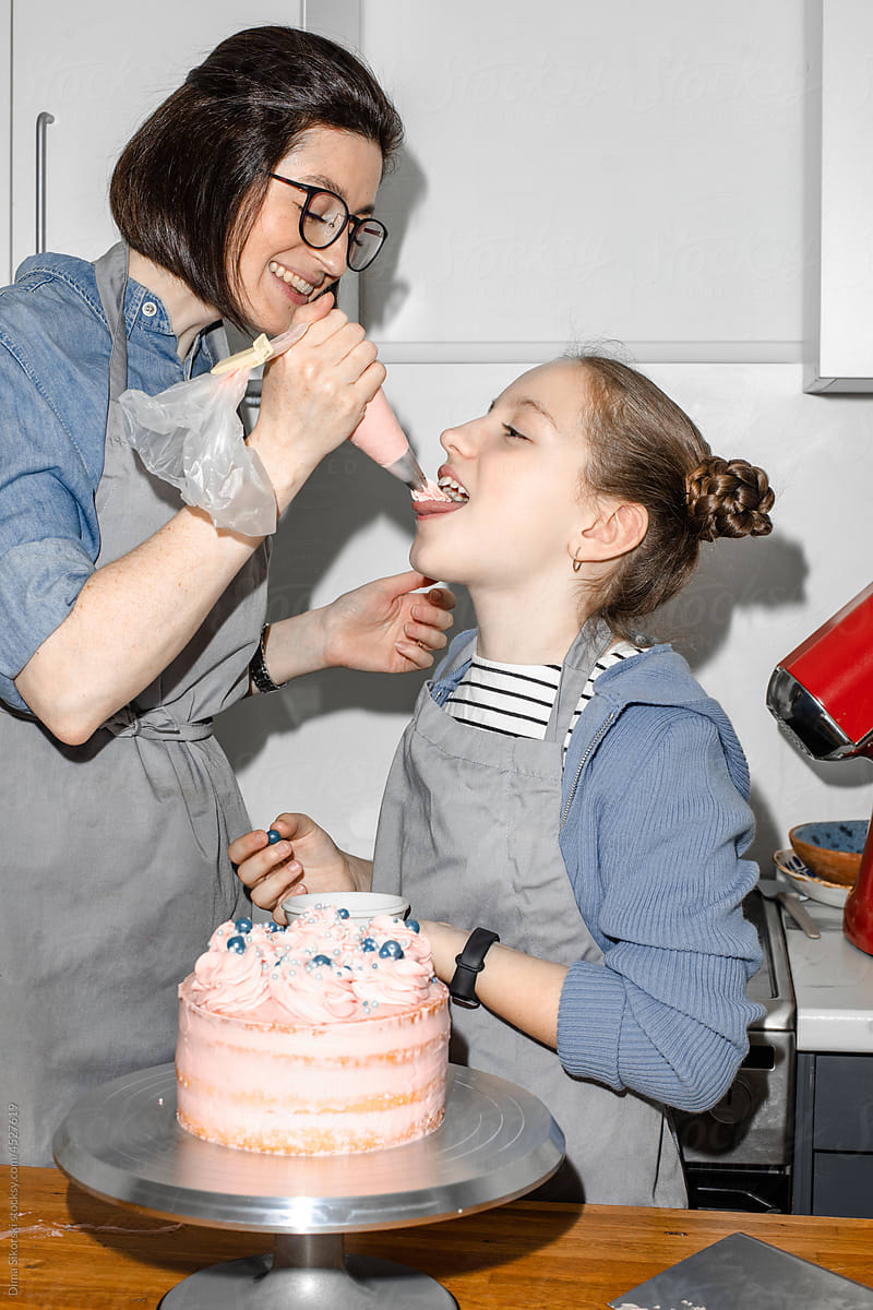 Mother feeds daughter cake cream, they are happy