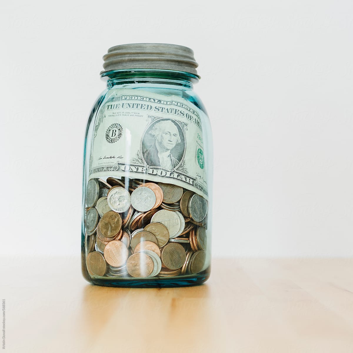 Jar filled with coins and dollar bills