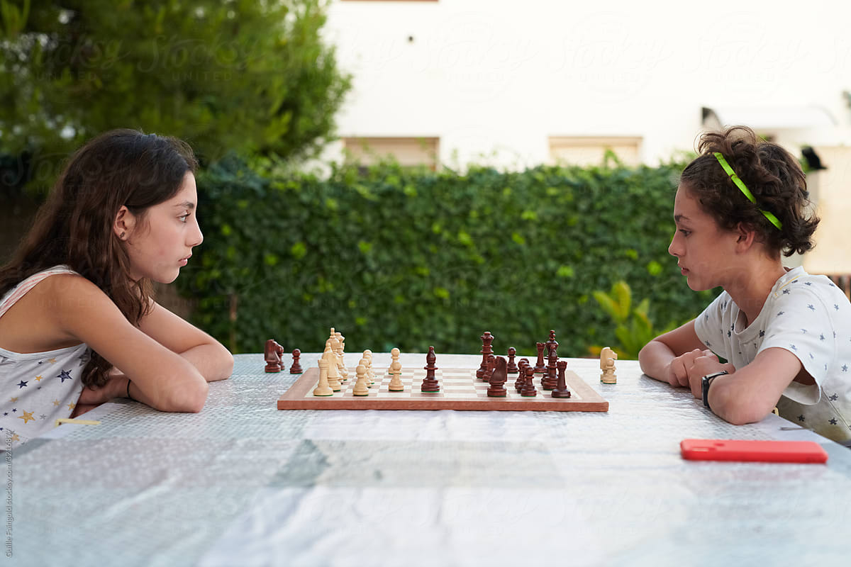 Smart siblings playing chess in garden