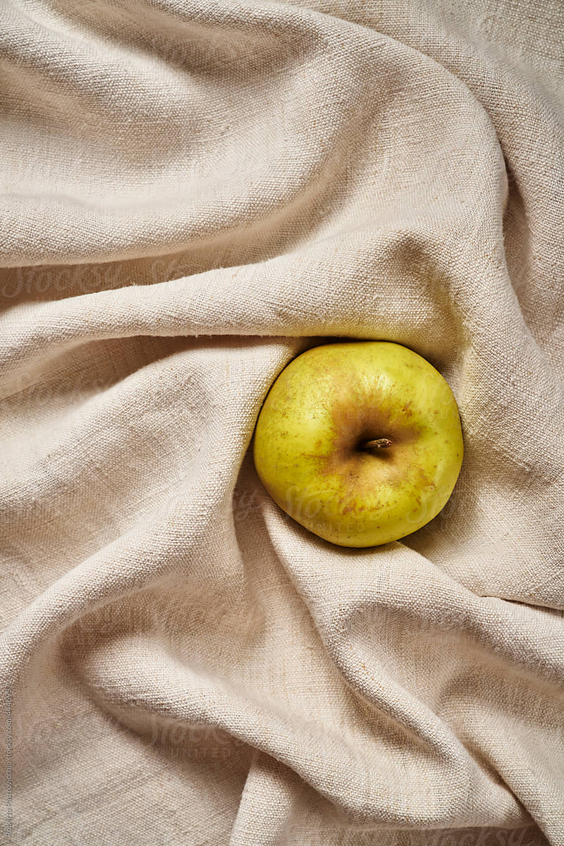 A yellow apple on a linen