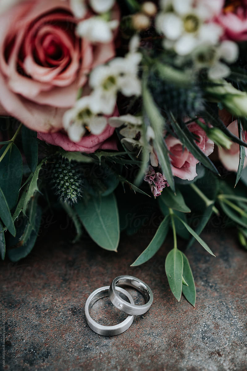 Two white gold or platinum wedding bands on display with flowers
