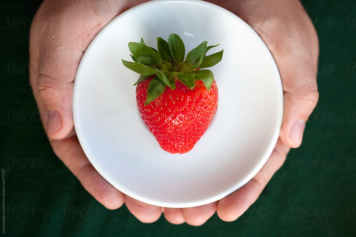 A fresh strawberry on a white plate