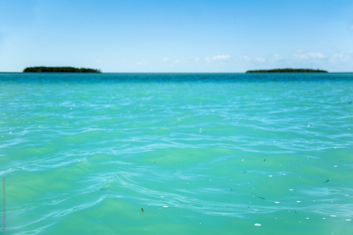 Close up shot of turquoise water with small islands on the horizon