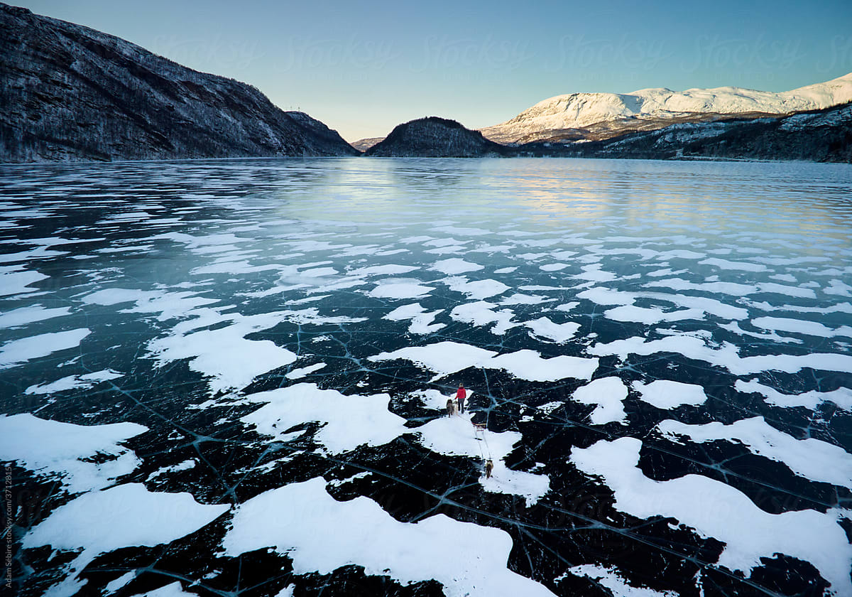 Vast Arctic lake ice - female with sledge dogs, aerial landscape