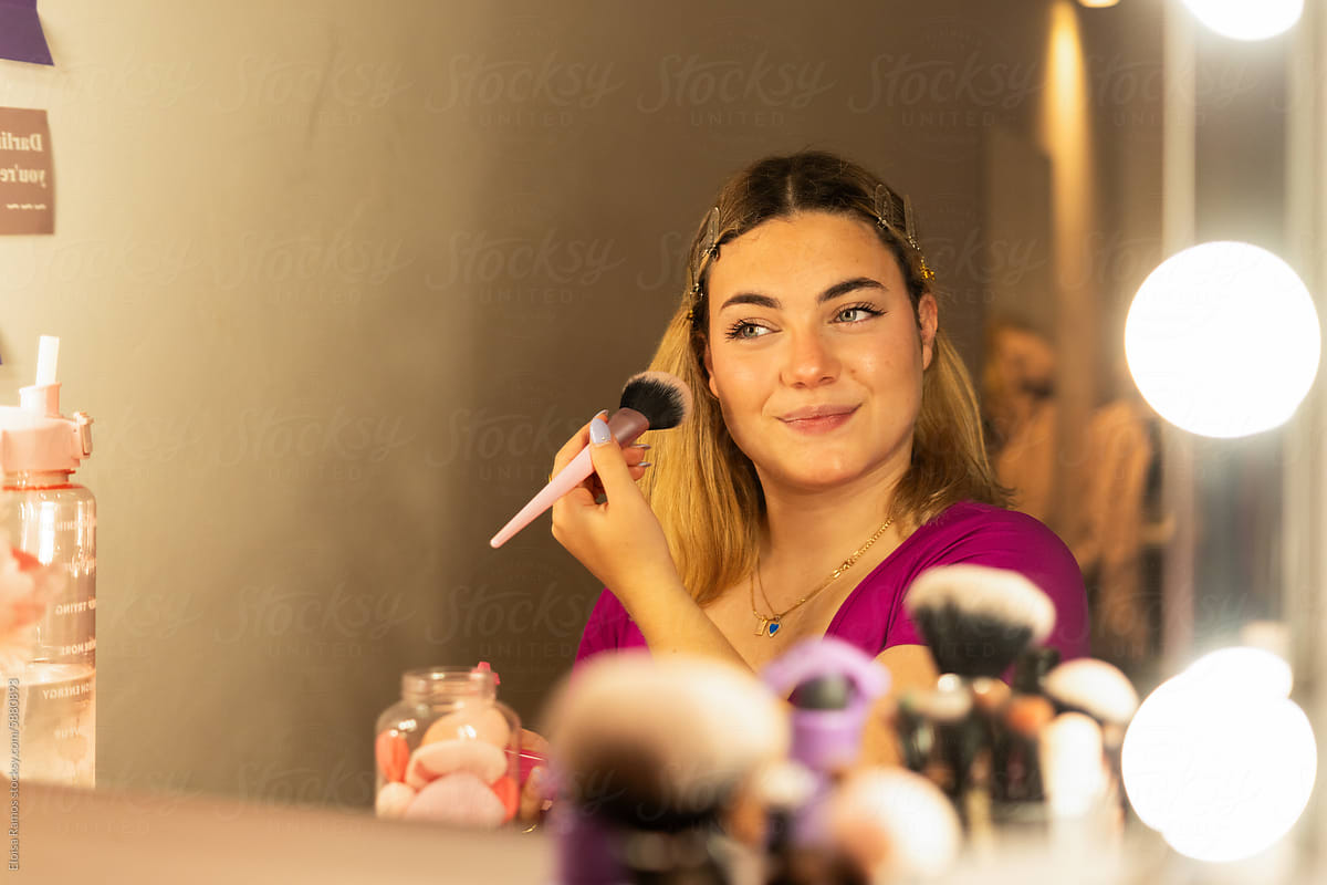 smiling teen girl Applying Blush in a vanity mirror