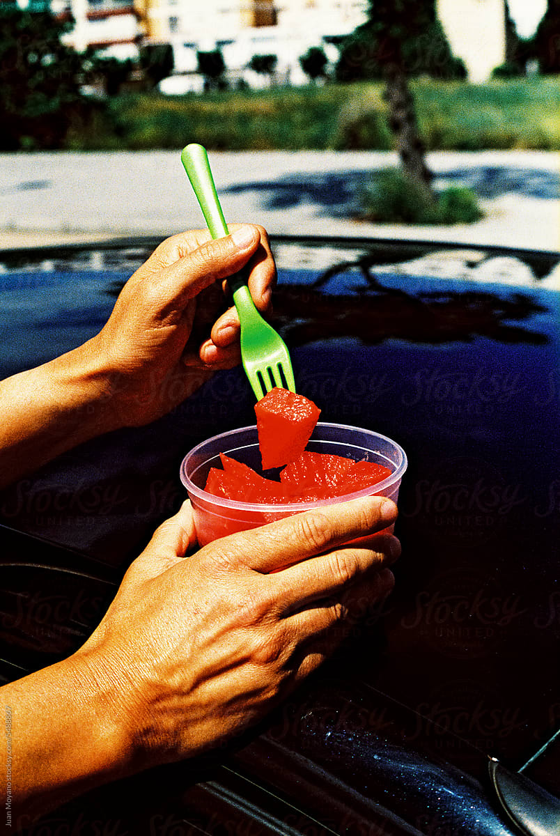 man eating watermelon next to a car, 35mm film