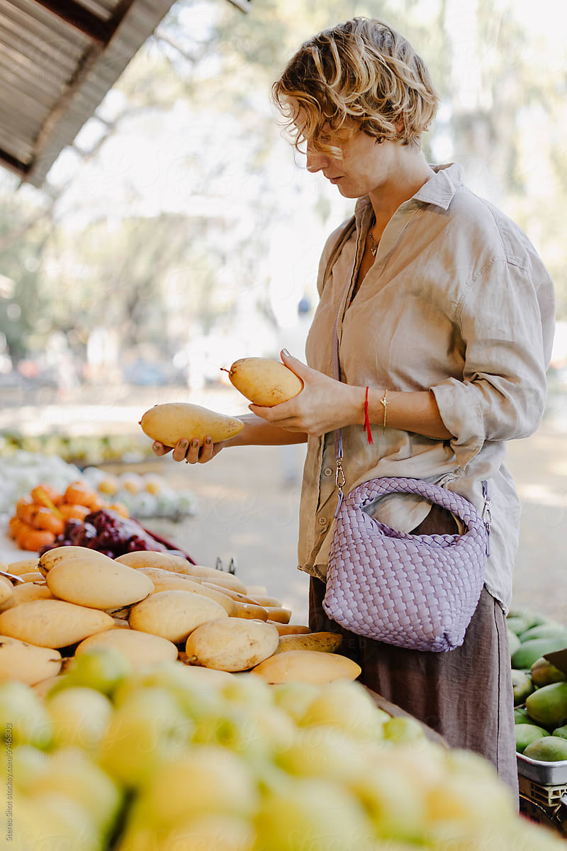 Woman with curly short hair buying fresh fruits at local market