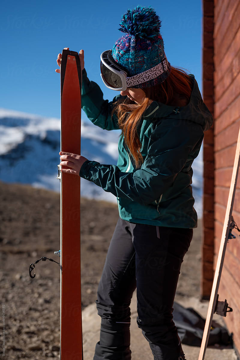 Woman preparing skis for mountaineering in highlands