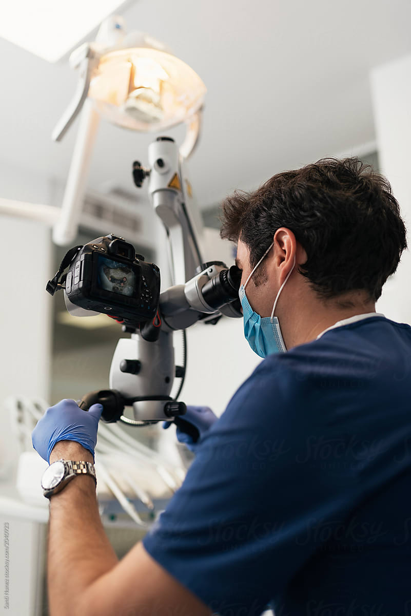 Dentist during a dental intervention using microscope.
