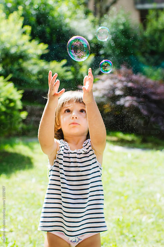 Funny little girl trying to grab a soap bubble