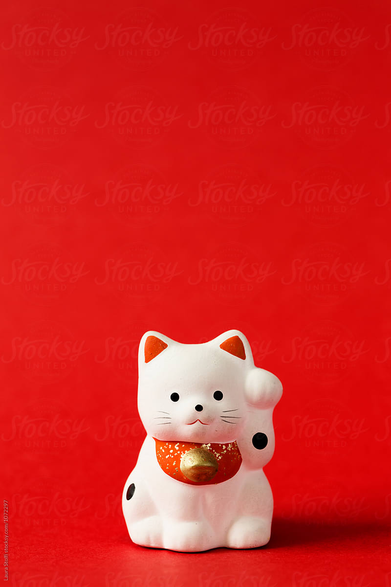 Close up og japanese beckoning cat in porcelain on red background
