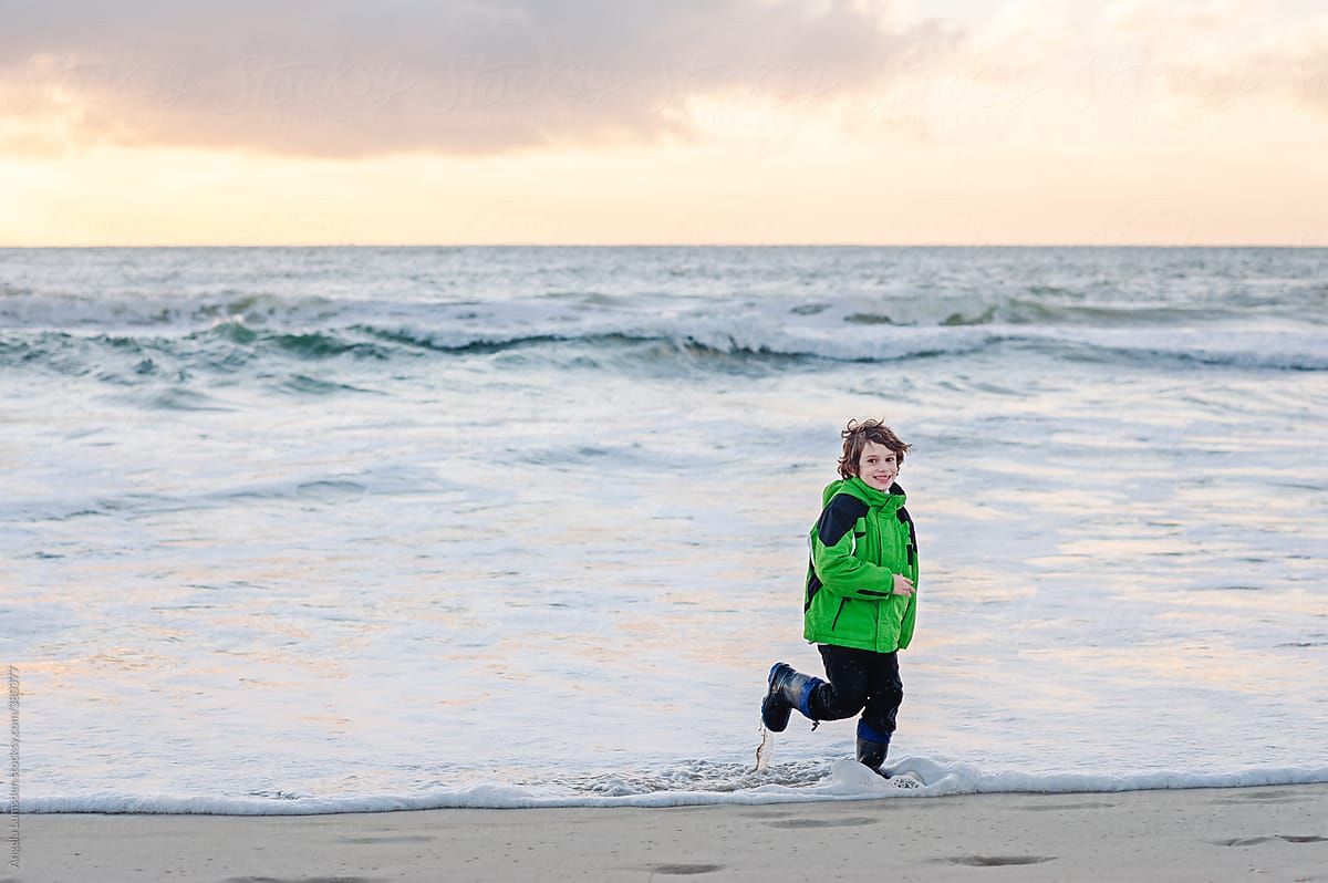 Boy having fun in the water at the beach in winter