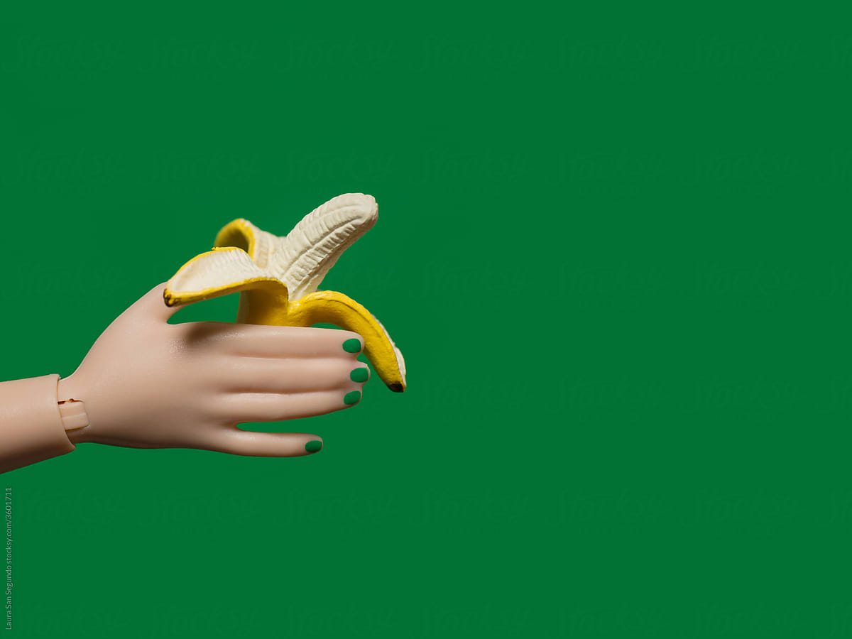 Plastic hand with green nails holding an open banana