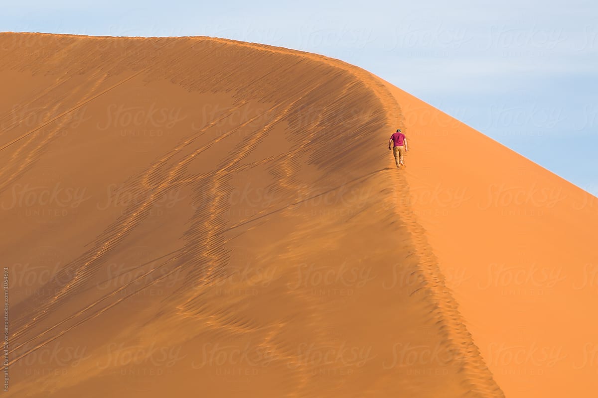 Person walking up a sand dune in the namib desert, Namibia, Africa
