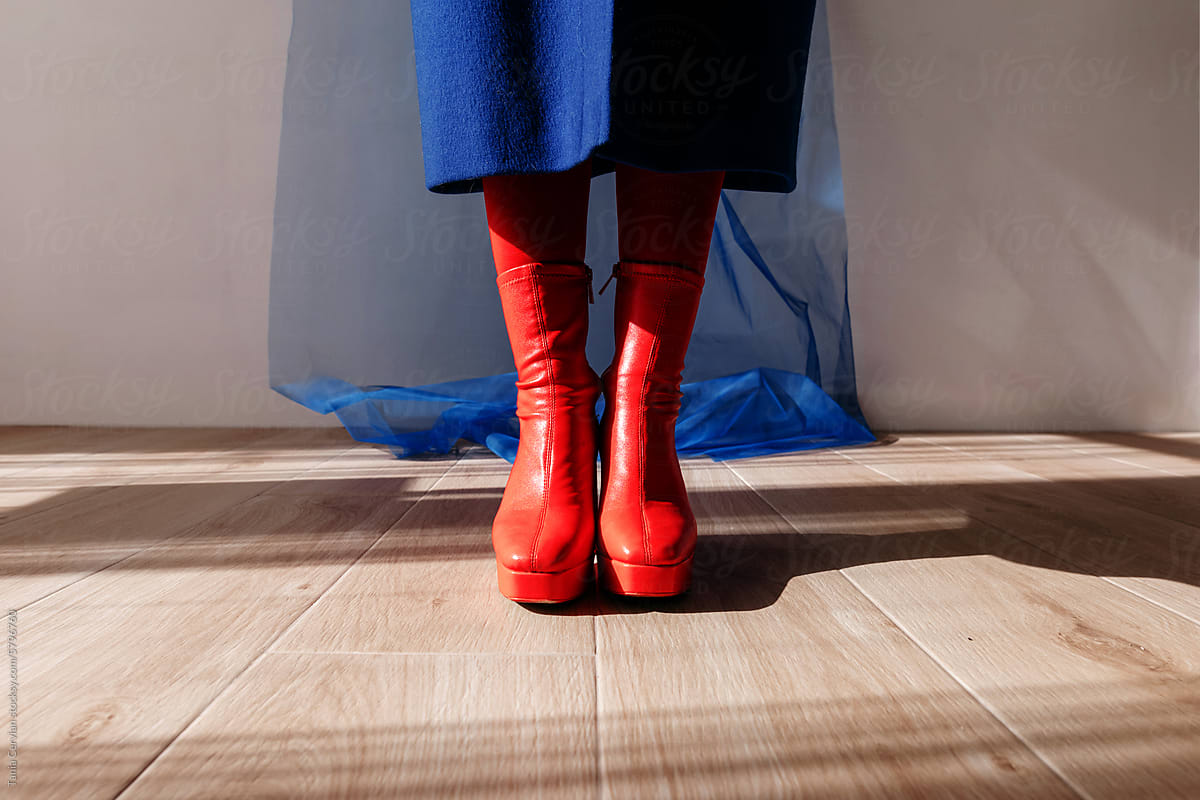 Legs of anonymous woman in red leather boots in studio