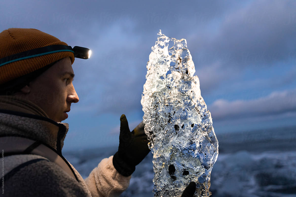 Hands holding a crystal-clear ice block against. Nature conservation
