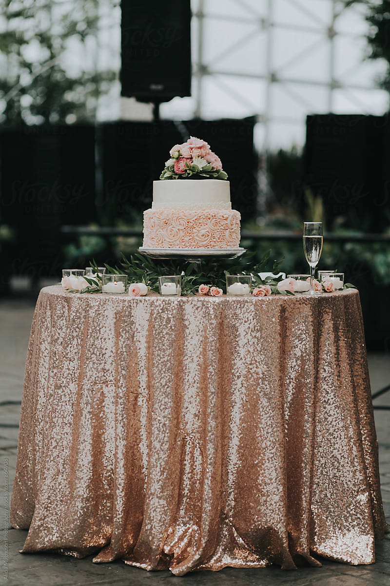 Detail of Blush Pink and White Wedding Cake on Candlelit Table with Champagne Glass