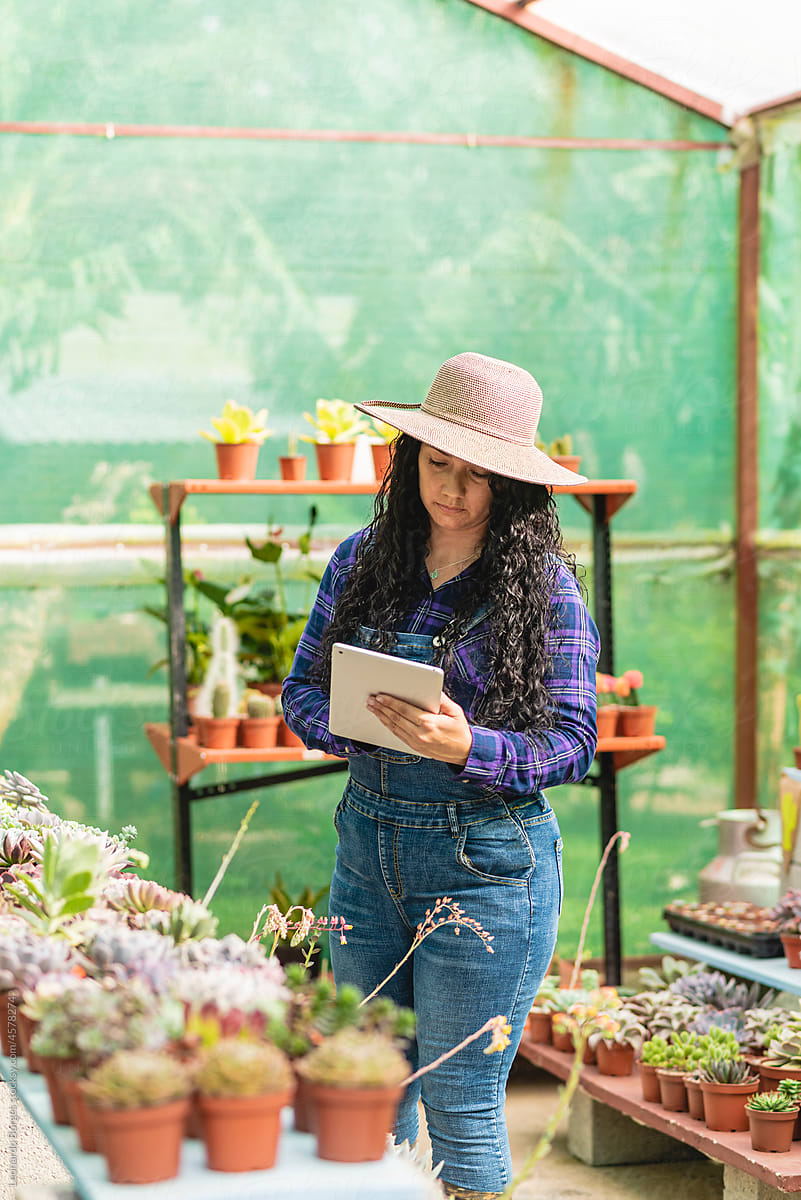 Woman wearing a hat using a tablet in her plant store