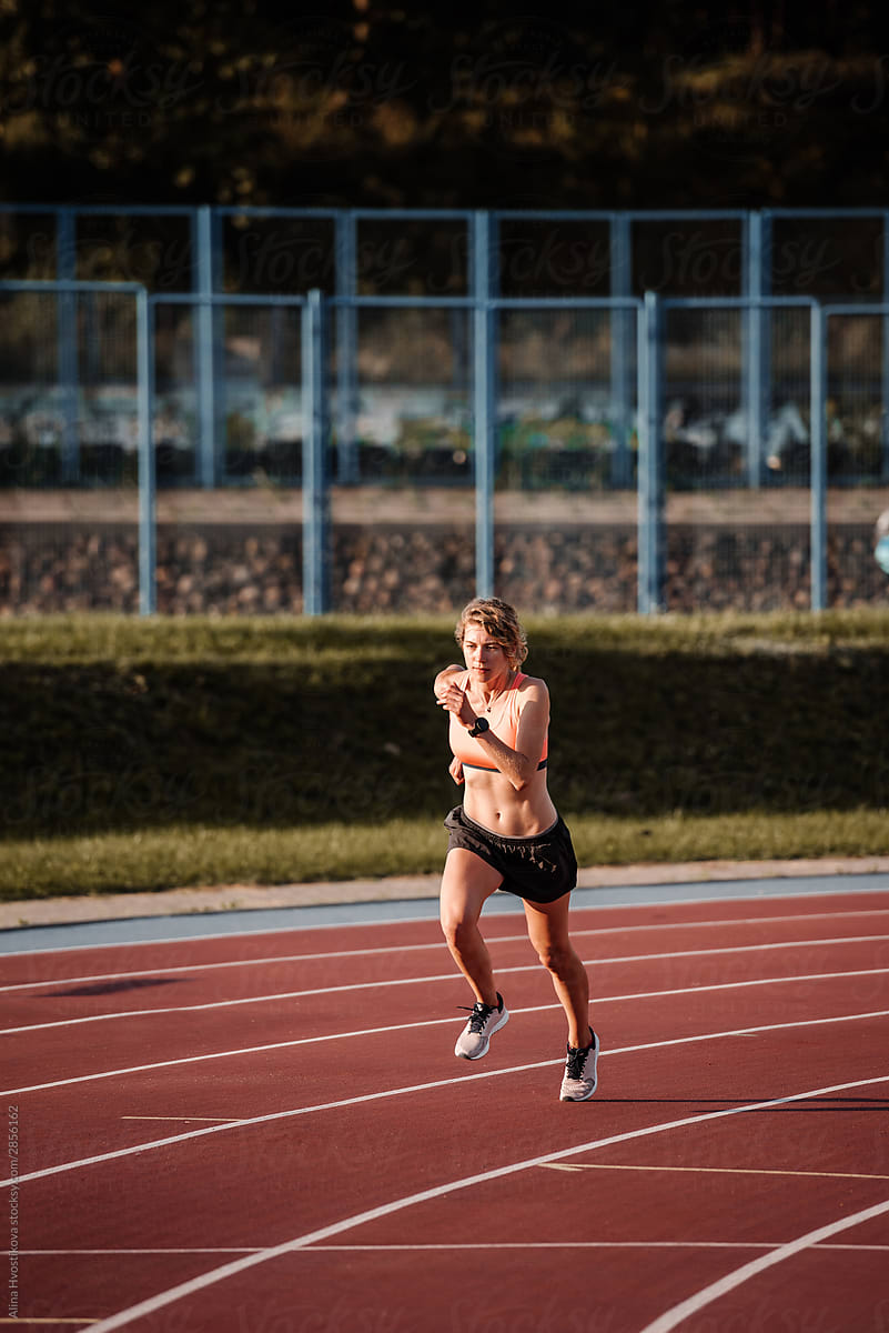 Strong athletic woman running on sports field