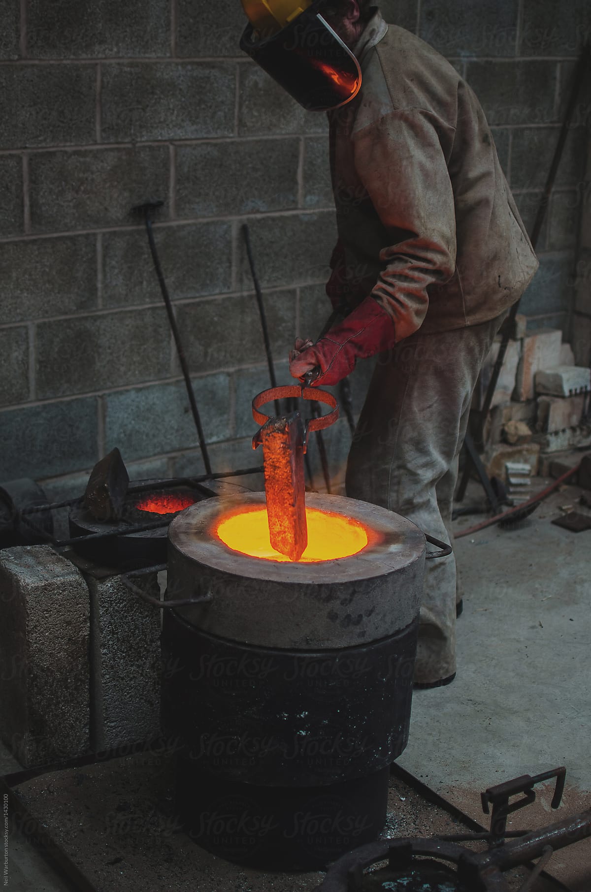 Worker lowering ingot into furnace