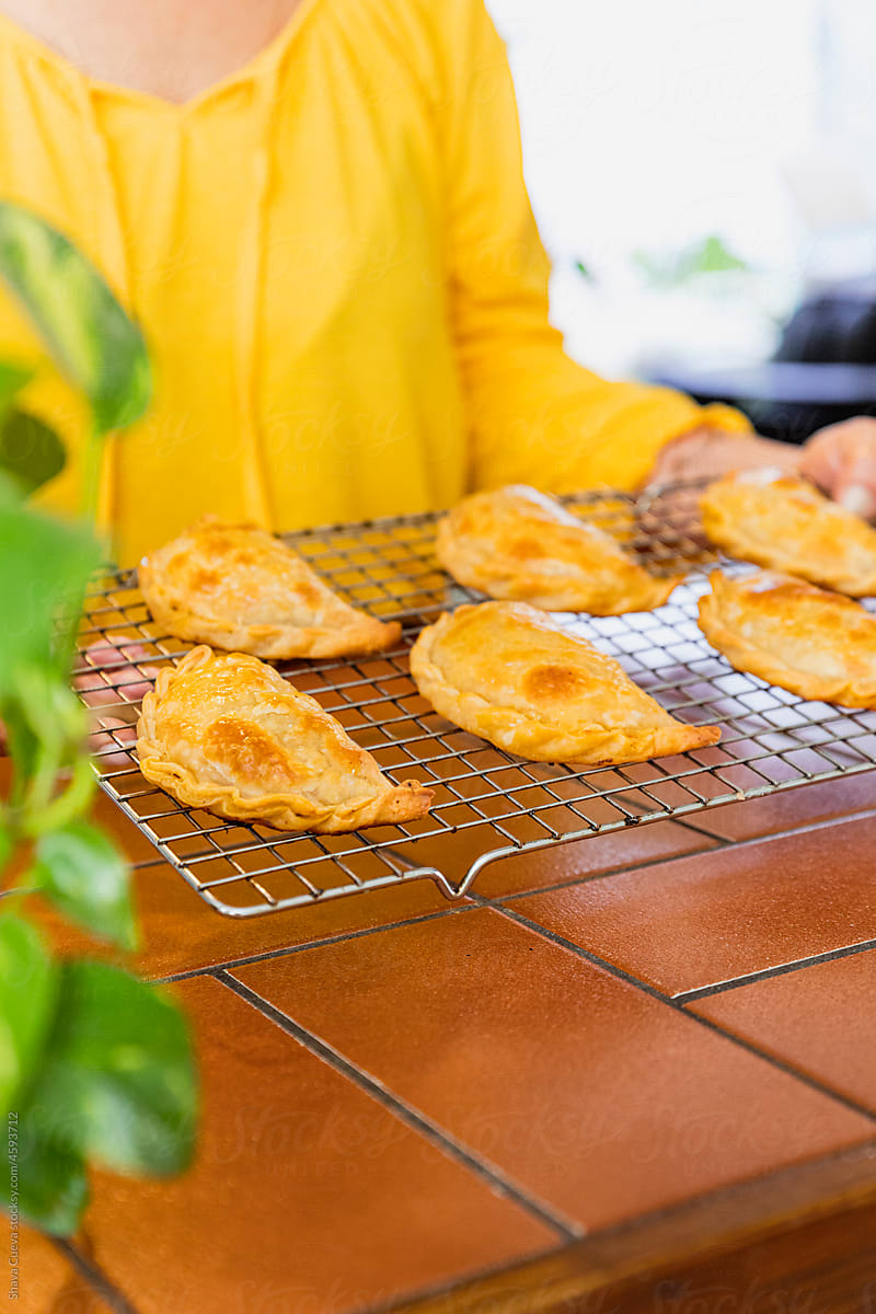 Woman in a yellow shirt holding a rack of Argentinian empanadas