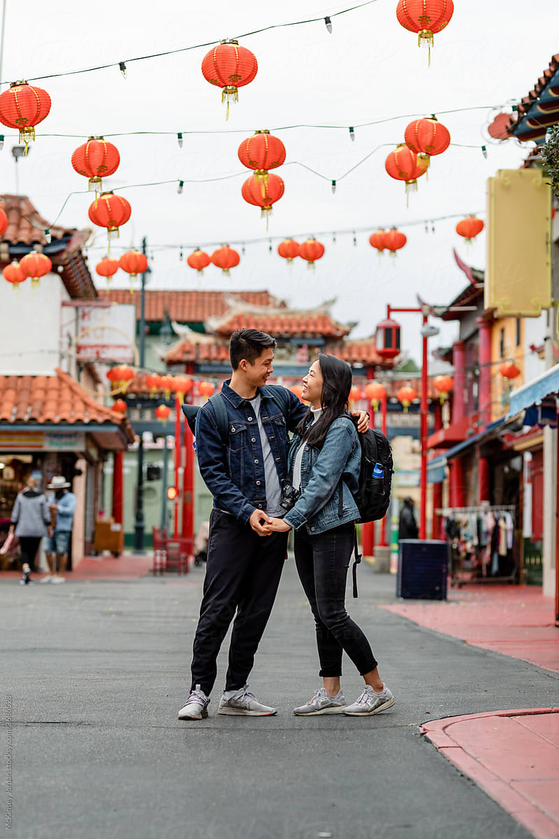 Young Asian Couple Embraces Lovingly Under Red Lanterns in Chinatown