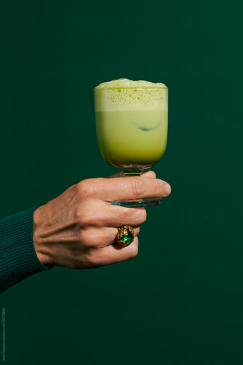 man has a glass with iced matcha latte in his hand