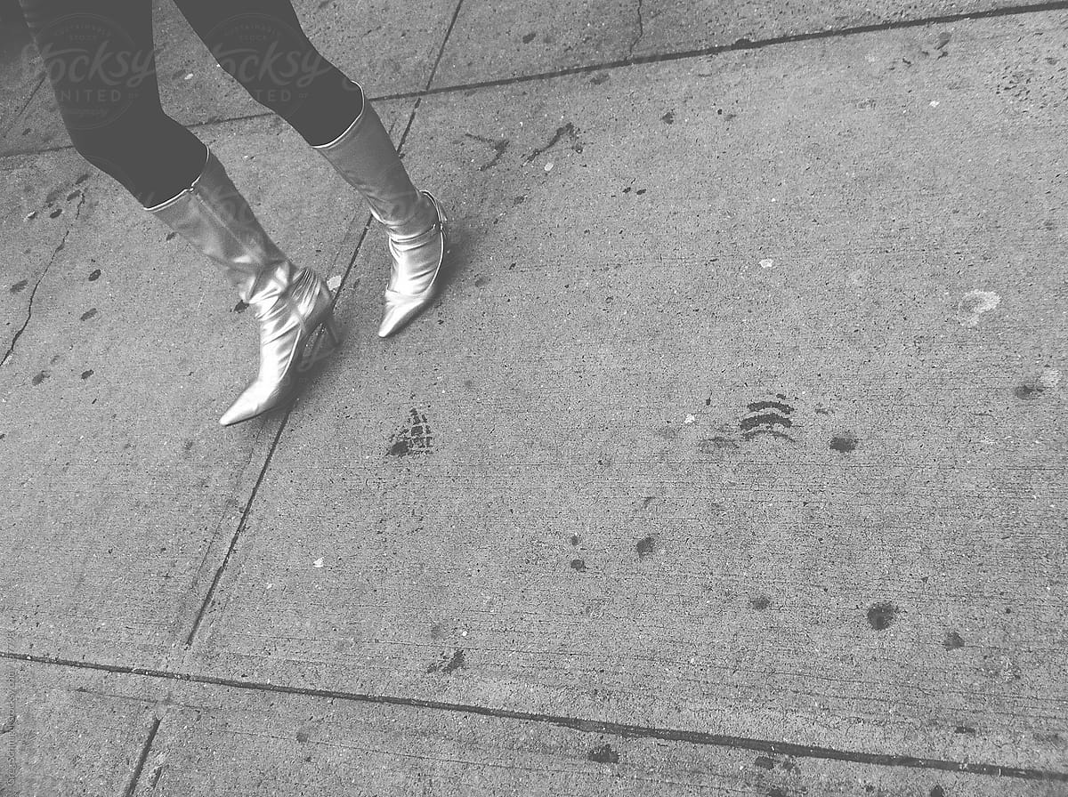 Girl in silver high heel boots on the sidewalk
