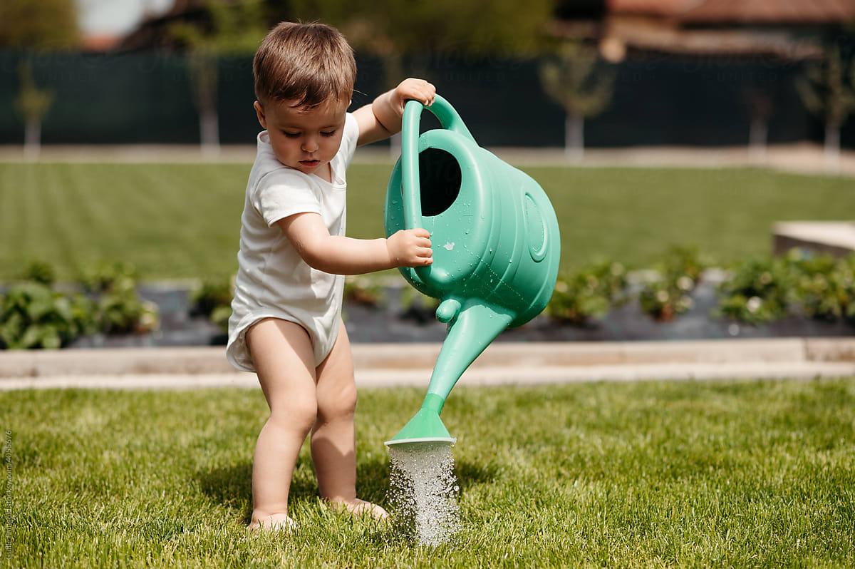 Baby watering grass with can.