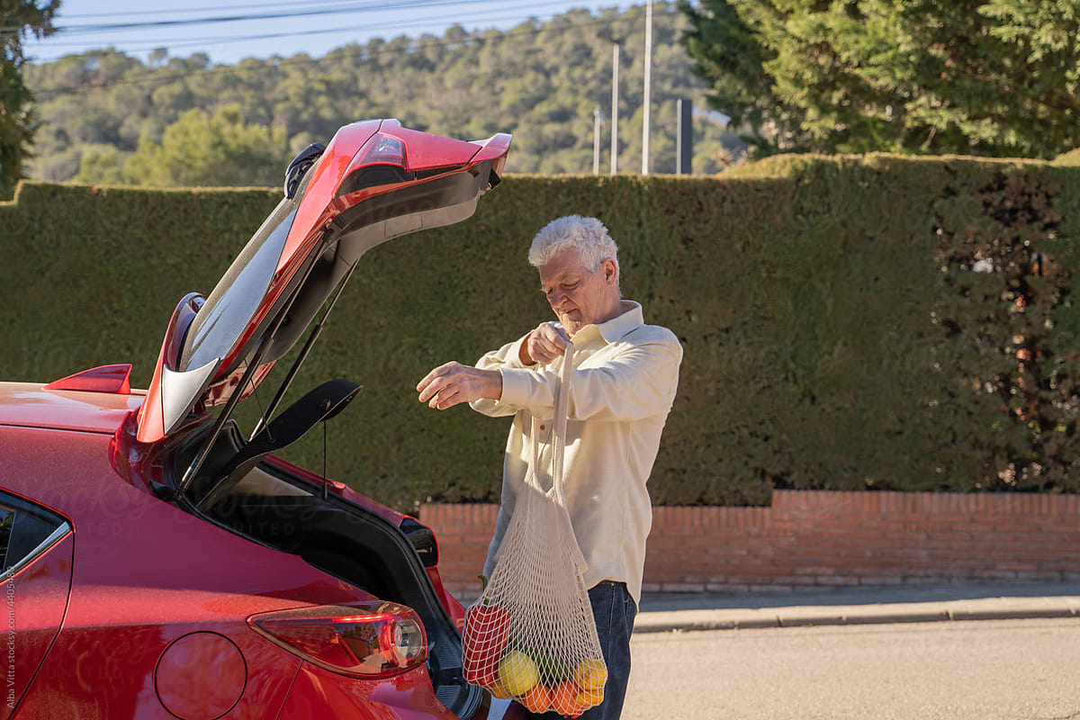Senior man picking the weekly grocery shopping from car