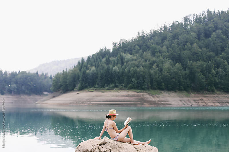 Woman sitting on the rock and reading a book