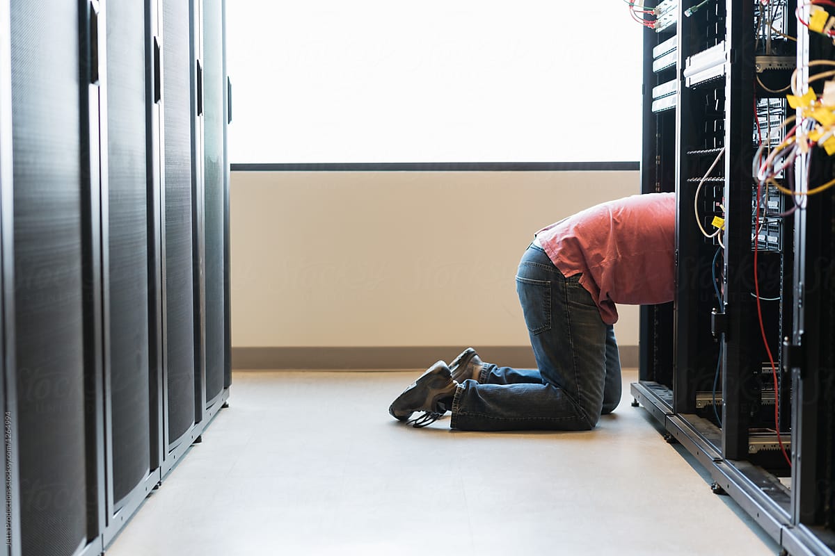 Lower half of a technician kneeling into a bank of servers in a