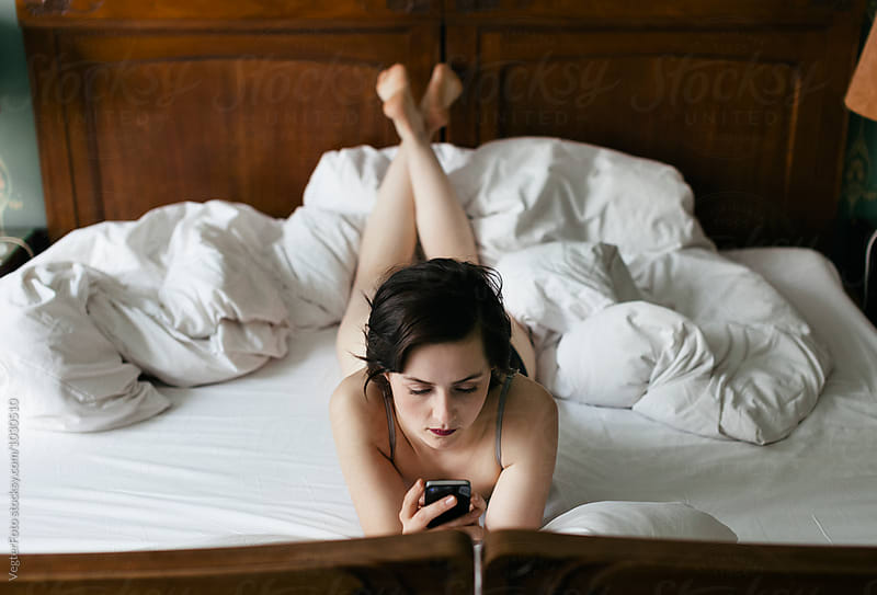 Woman in Hotel bed using Cell Phone
