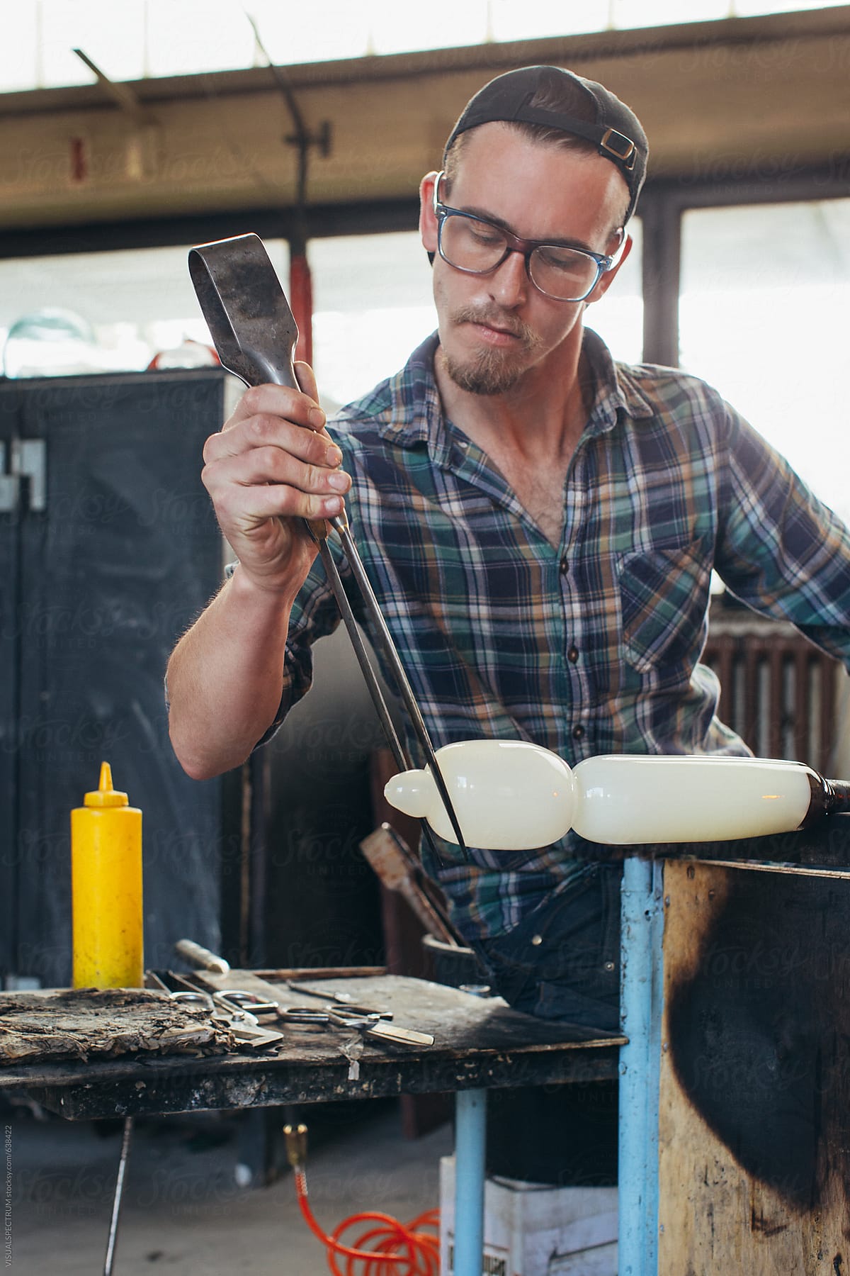 Artisan Glass Workshop - Portrait of Male Hipster Artist Shaping Hot Glass With Jacks
