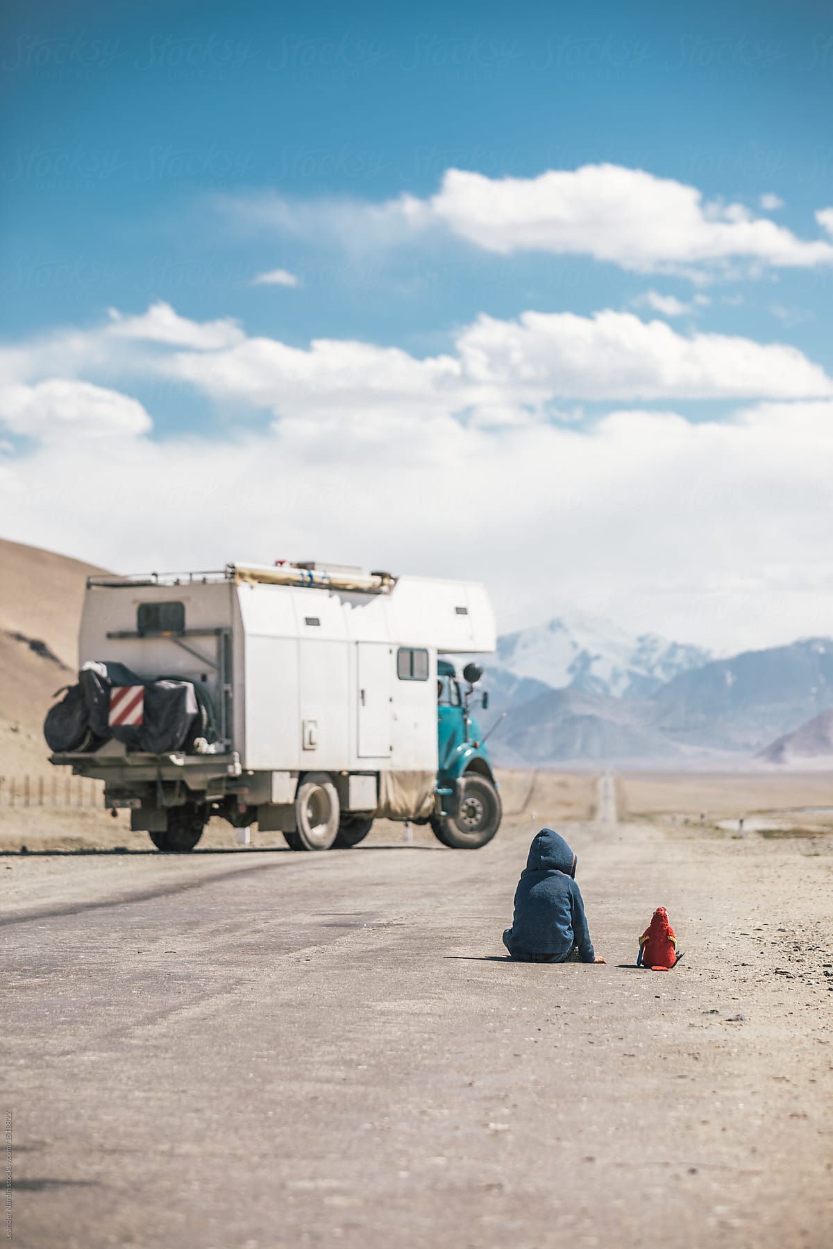 young boy sitting on a road on the pamir highway